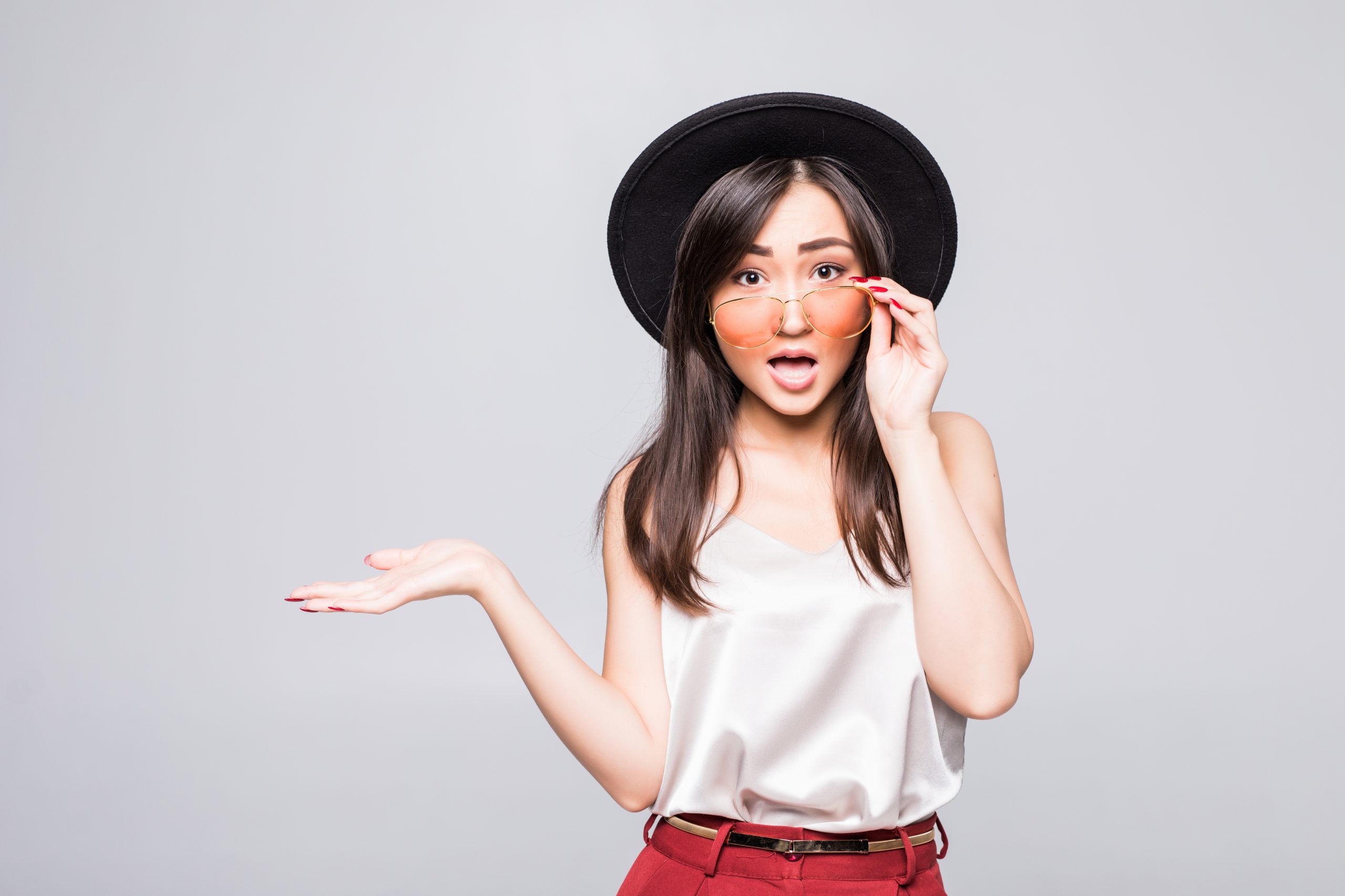 Young asian woman with sunglasses gesture with hands on white background